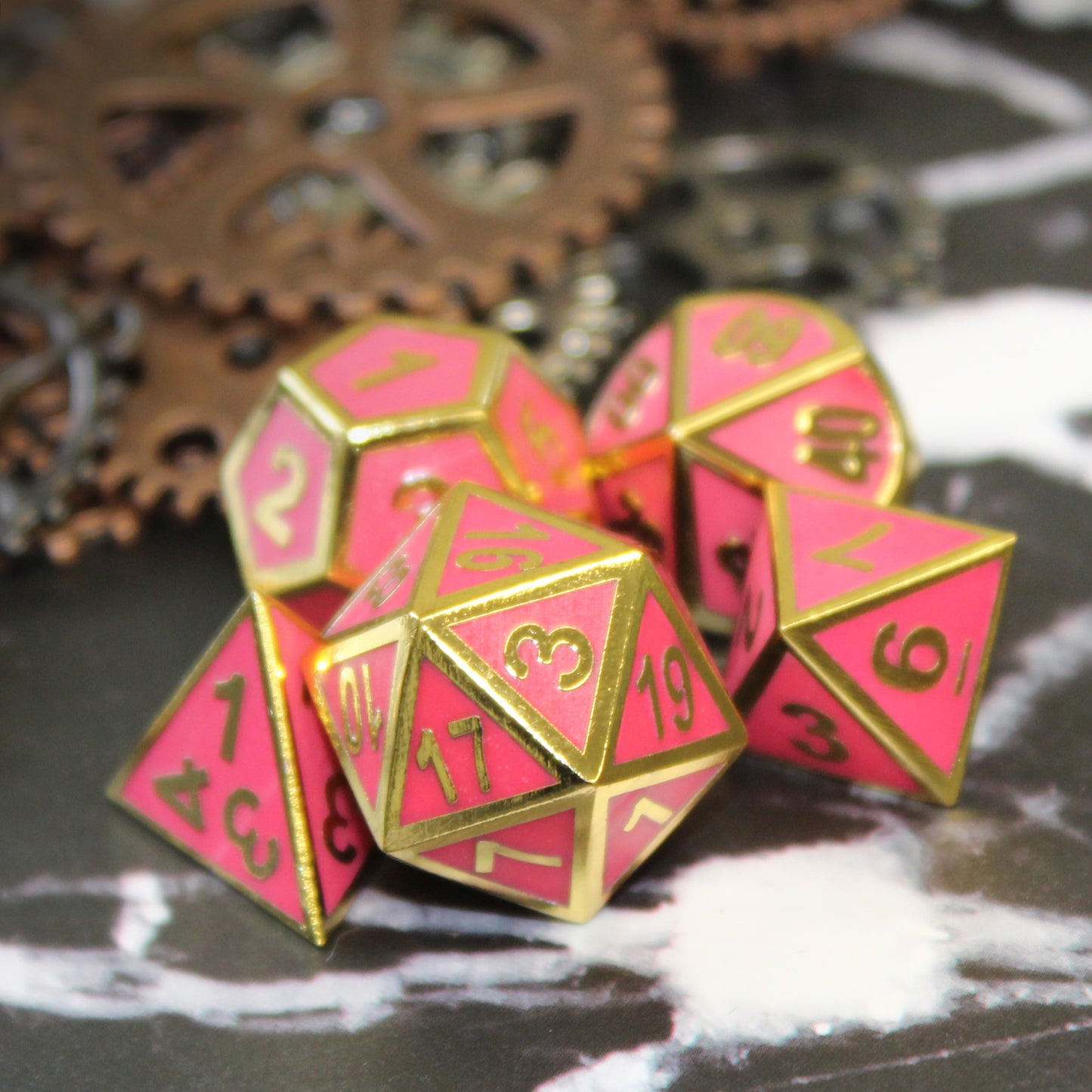 Five pink imperial dice arranged on a white and black surface with bronze and silver gears in the background.
