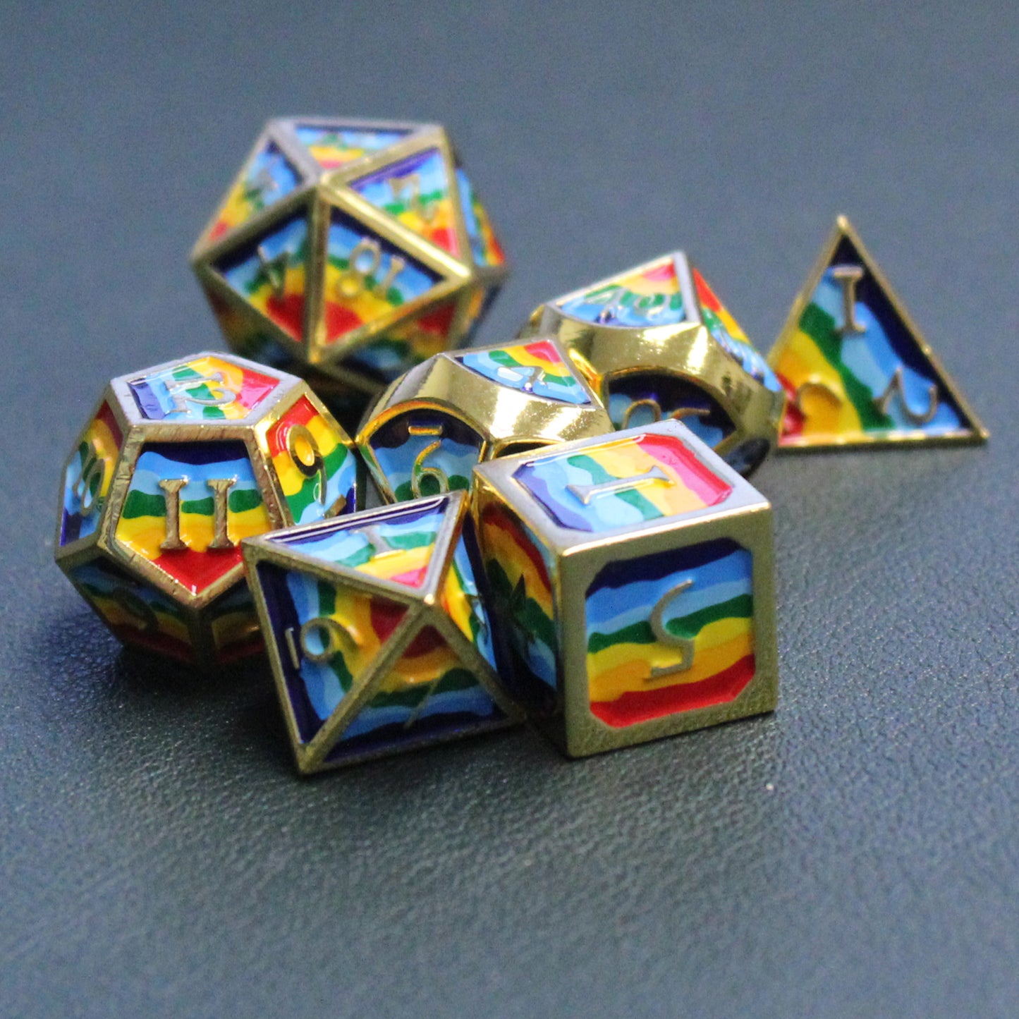 Photograph of rainbow-striped RPG dice with golden numbers and edges on a black surface.