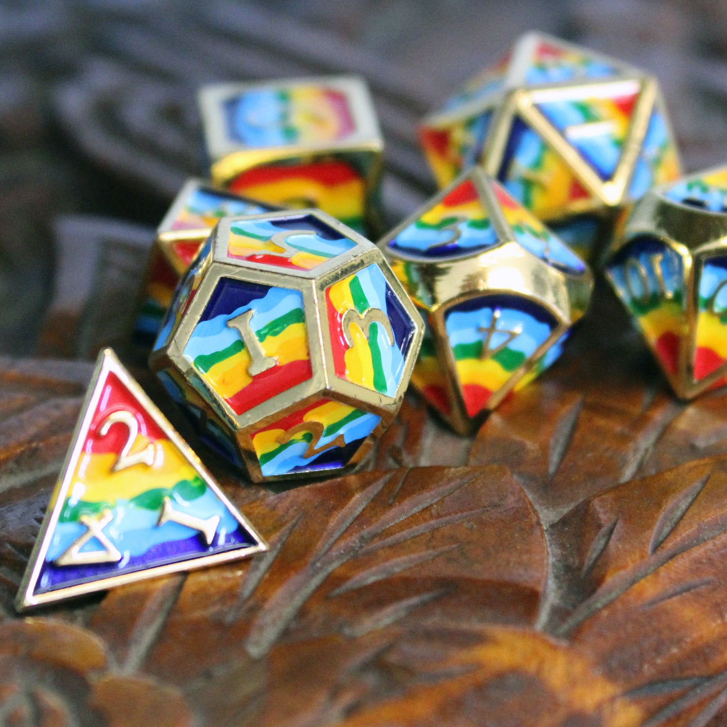 Closeup photograph of rainbow-striped RPG dice with golden numbers and edges on a carved wooden surface