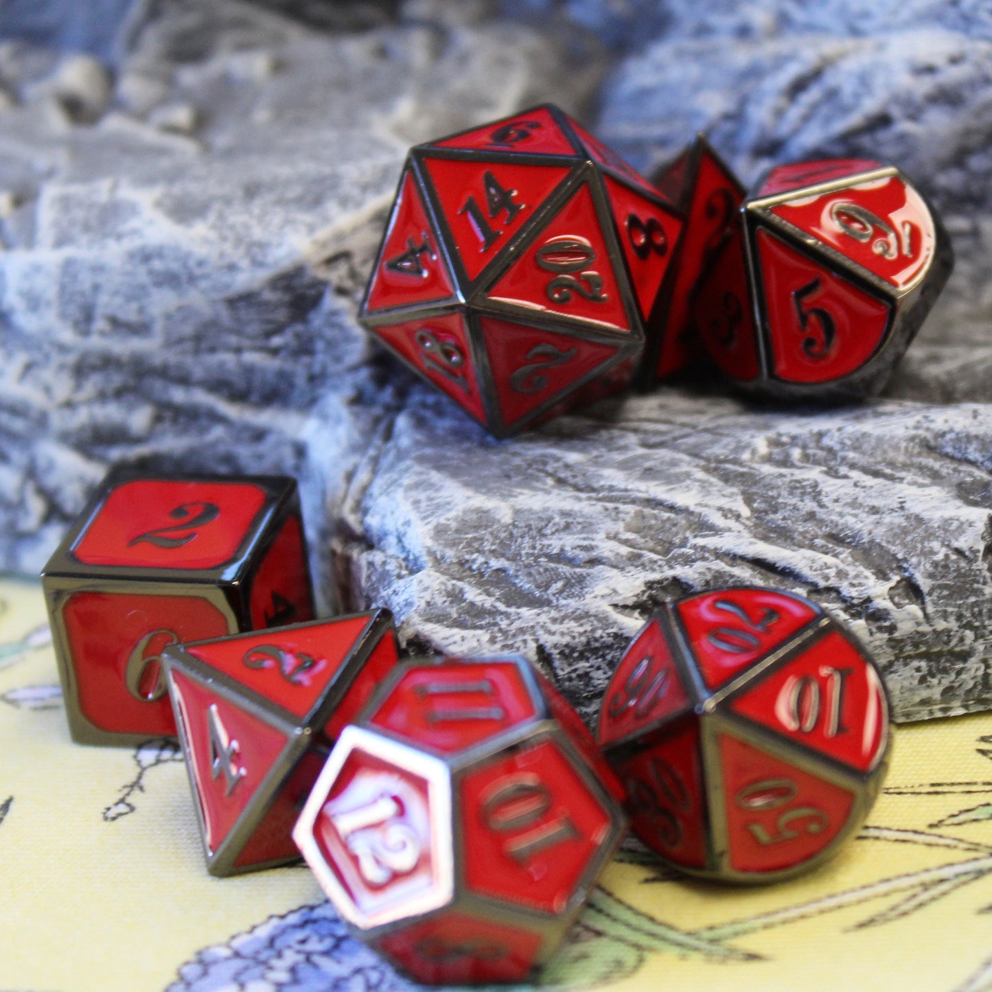 Metal Imperial Red dice set scattered over a green floral fabric surface and rocky set piece
