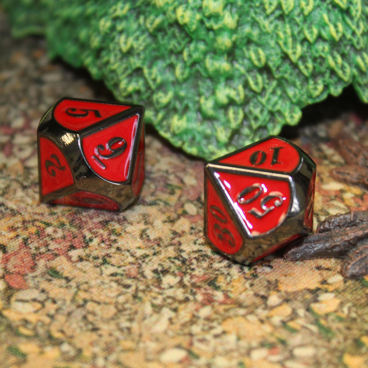 Two dice from the Imperial Red dice set on a play mat with a foliage set piece behind them.