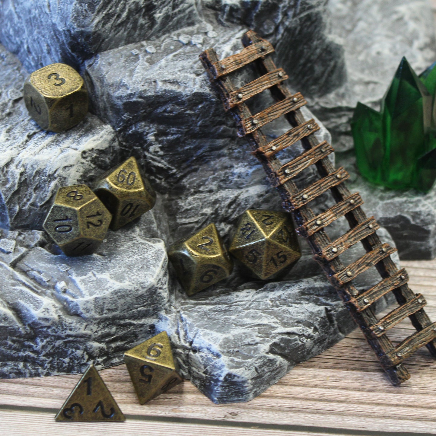 Primordial gold dice set scattered on a rocky set piece with a ladder leaning against it