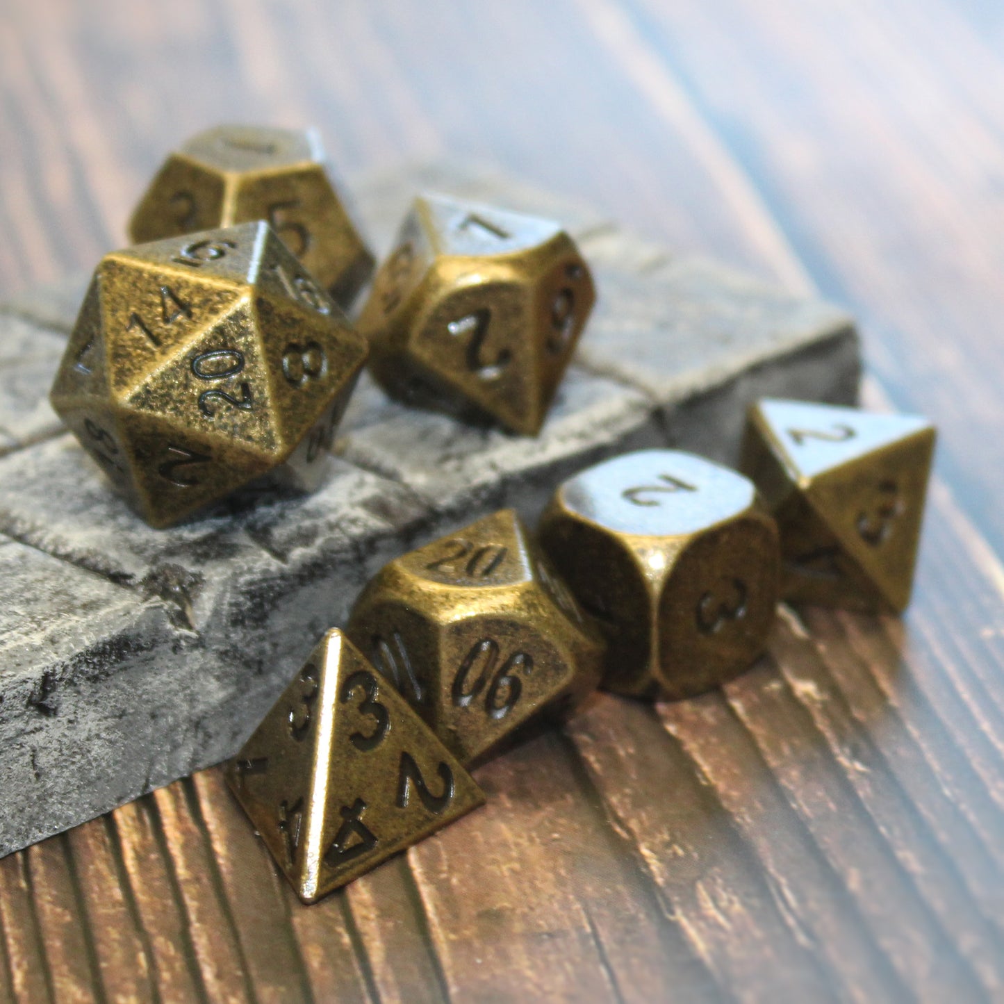 Primordial gold dice set partially scattered on a wooden surface and partially on a raised stone floor set piece