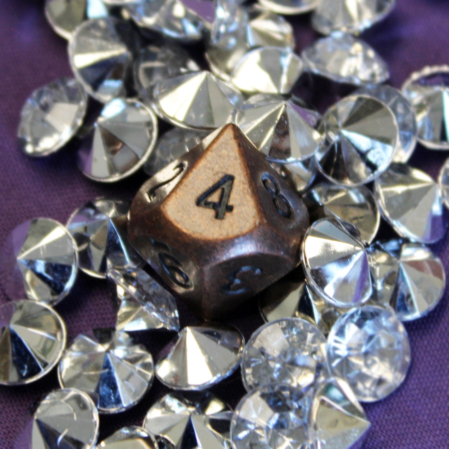 Primordial copper D10 die on a purple fabric surface, surrounded by silvery gems
