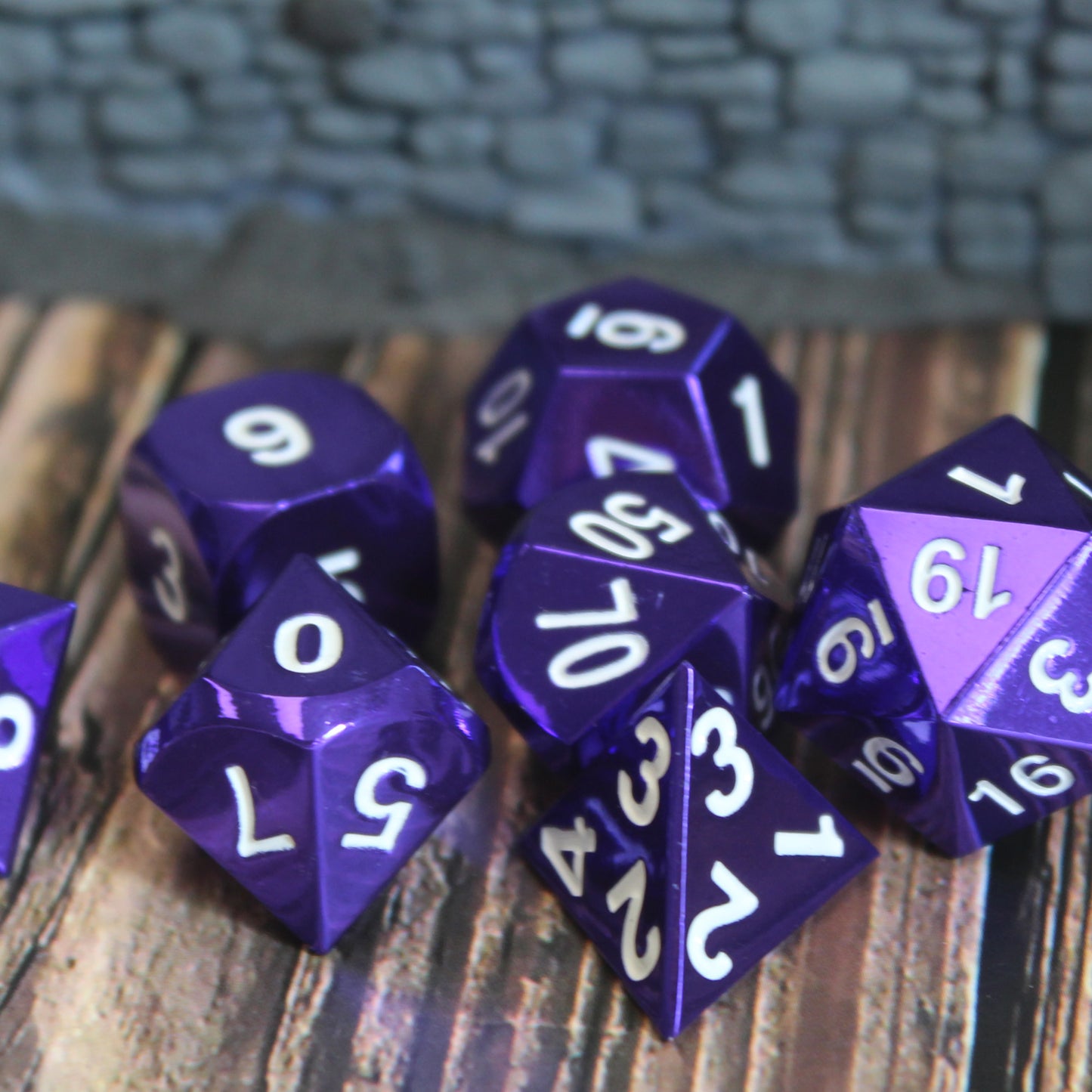 Close-up of Radiant Purple dice set on a wooden surface, with stone wall set piece behind them