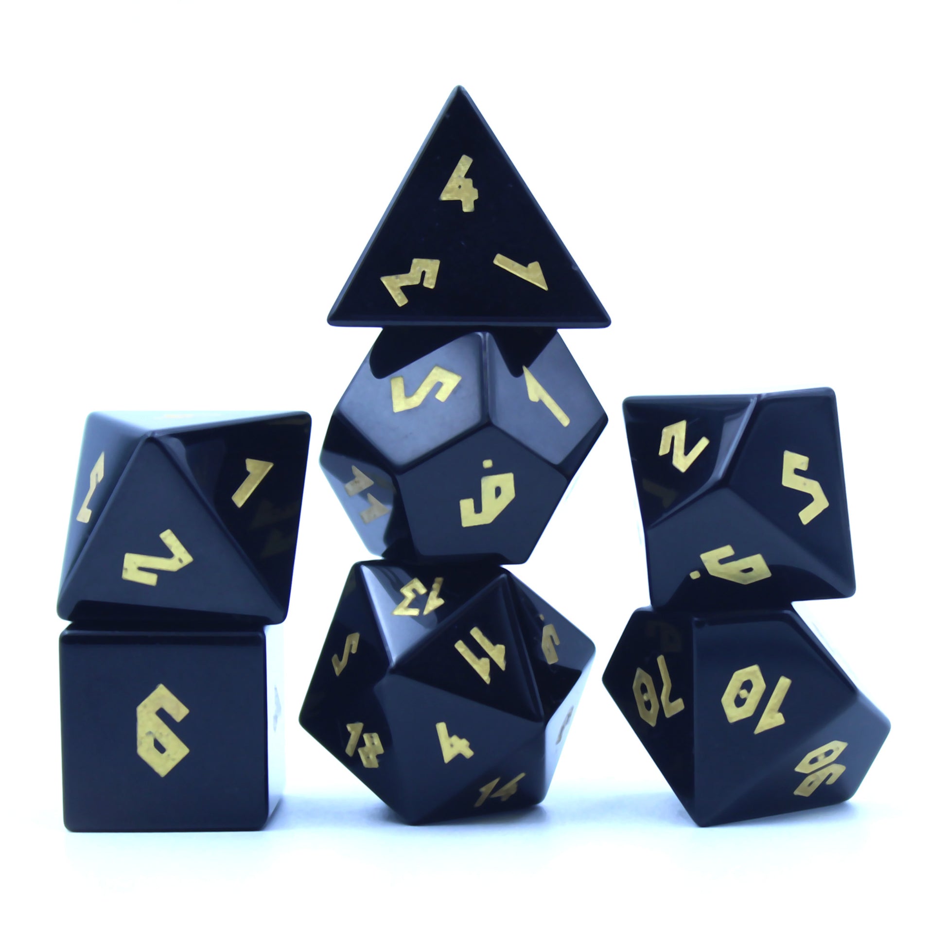 Stacked obsidian dice set on a white background, showcasing elegant contrast between black gemstone and gold foil numbers for tabletop RPGs.