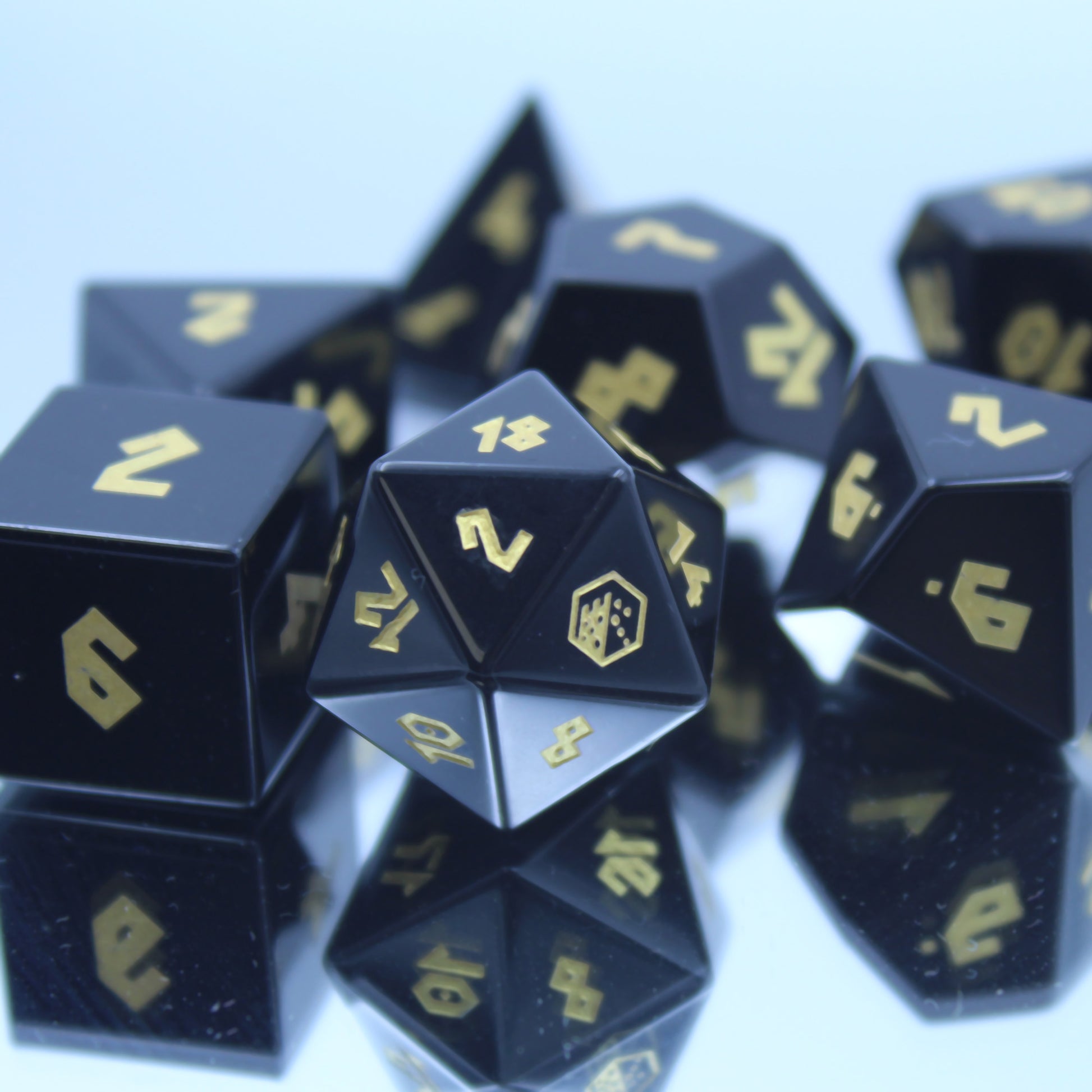 Obsidian dice set displayed on a mirror, reflecting deep black hue and luxurious finish, perfect for Dungeons and Dragons sessions.