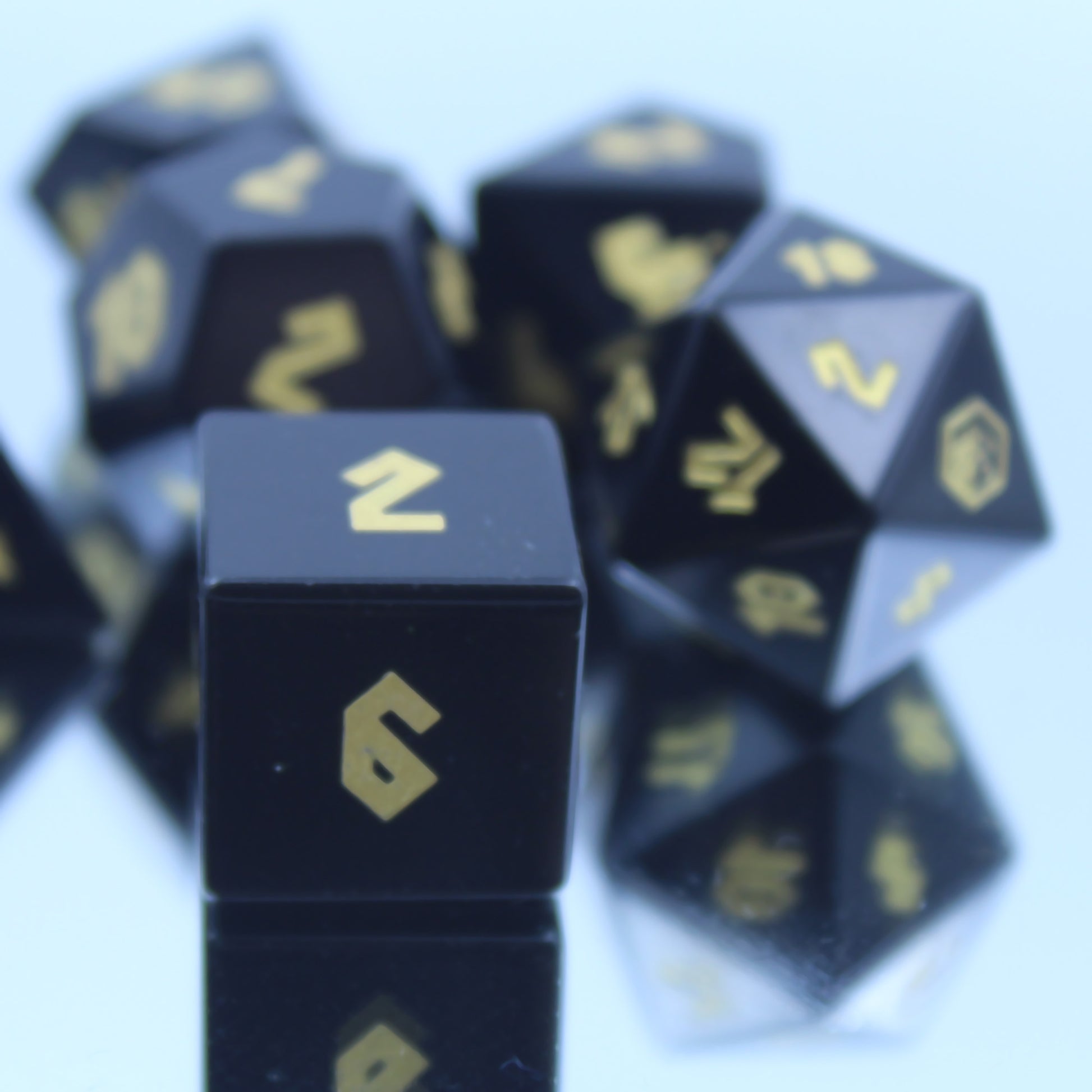Close-up of D6 die on a mirror, emphasizing jet black obsidian and bright gold numbering for an elegant addition to your RPG adventures.