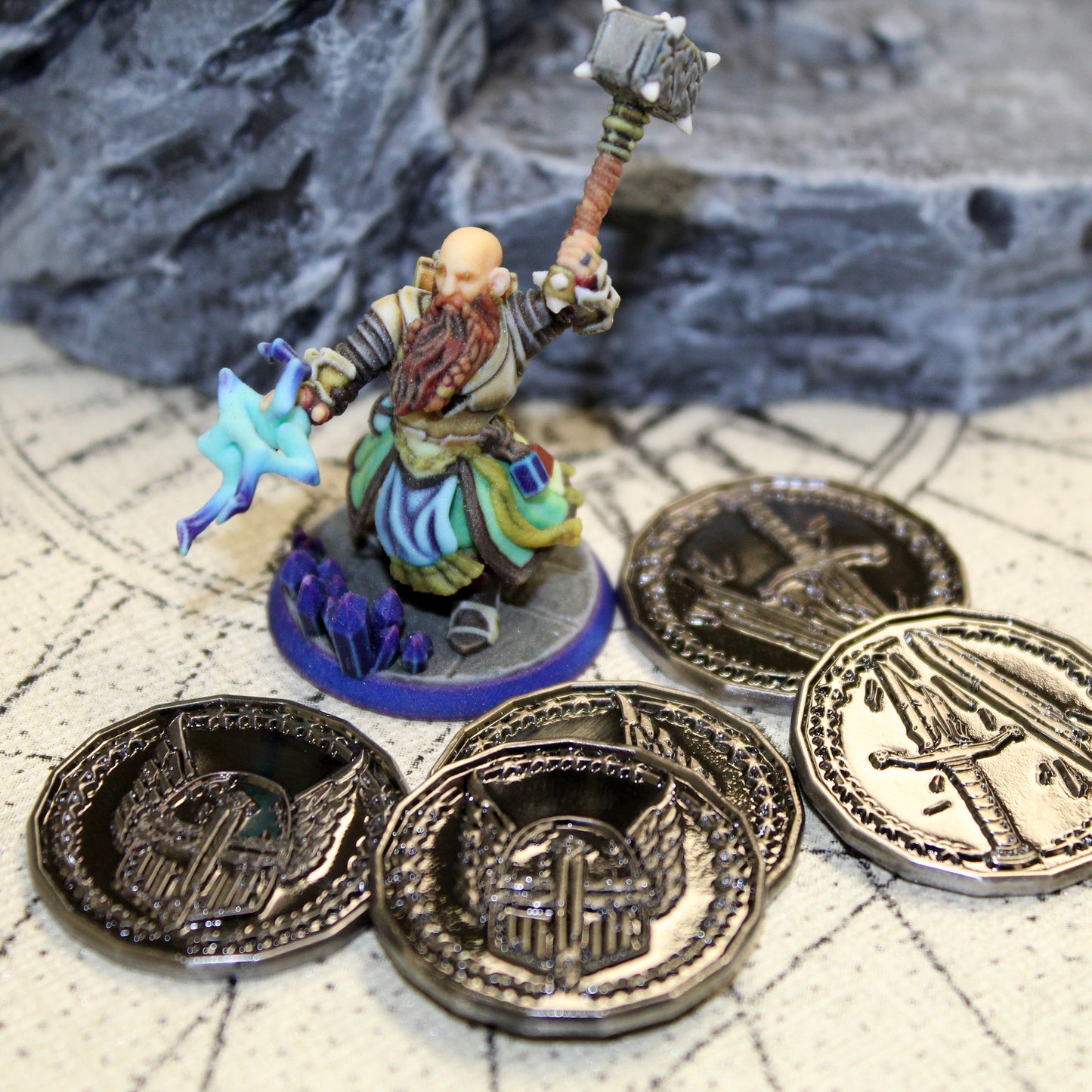 Five gold paladin character tokens in front of a miniature figure and a rocky set piece.