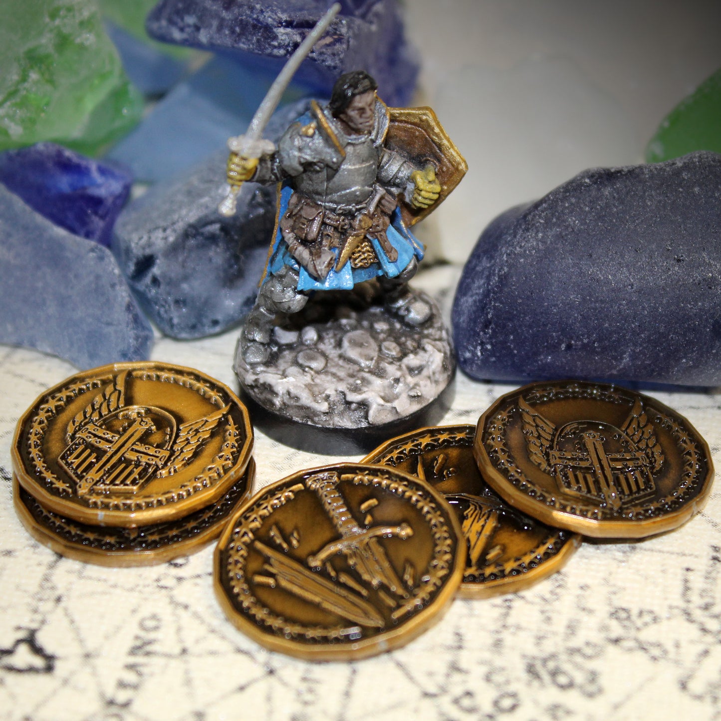 Antique gold finished Paladin Character coins arranged around a paladin miniature on a printed map surface with sea glass in the background. These coins are sized for a 1 inch battle map.