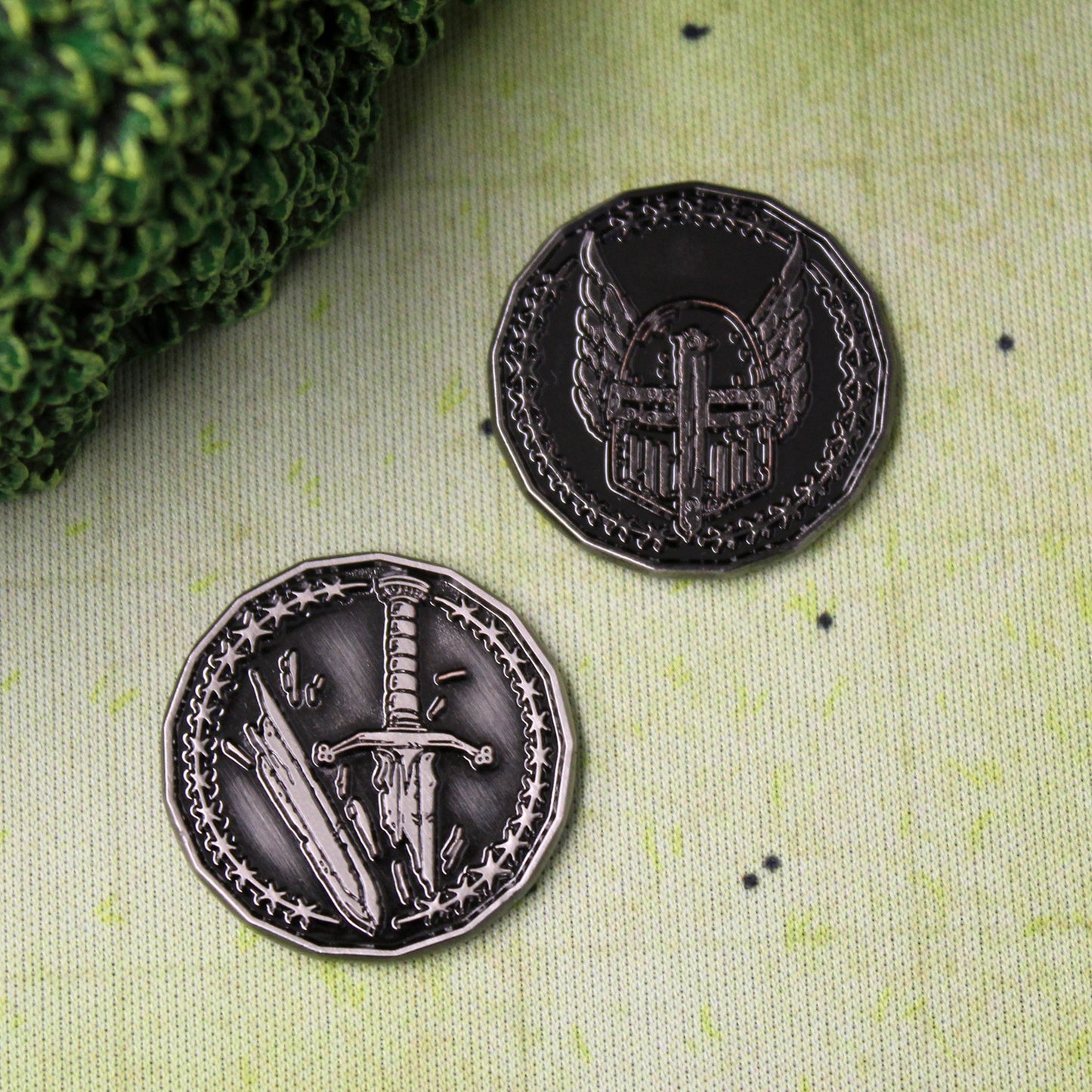 Two silver finished Paladin Character coins arranged on a printed map surface. The coins are flipped to opposite sides, one coin displaying the winged helmet and the other coin displaying the broken sword. These coins are sized for a 1 inch battle map.