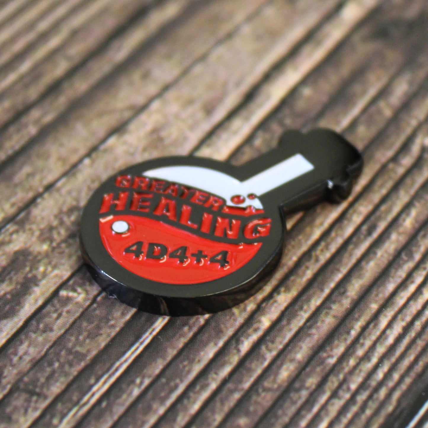Potion of Greater Healing Token on dark wood surface. Token is shaped like a round bottom boiling flask, halfway filled with the design of red bubbly liquid and the words "greater healing" written in red. On the liquid is a black letting "4D4+4".