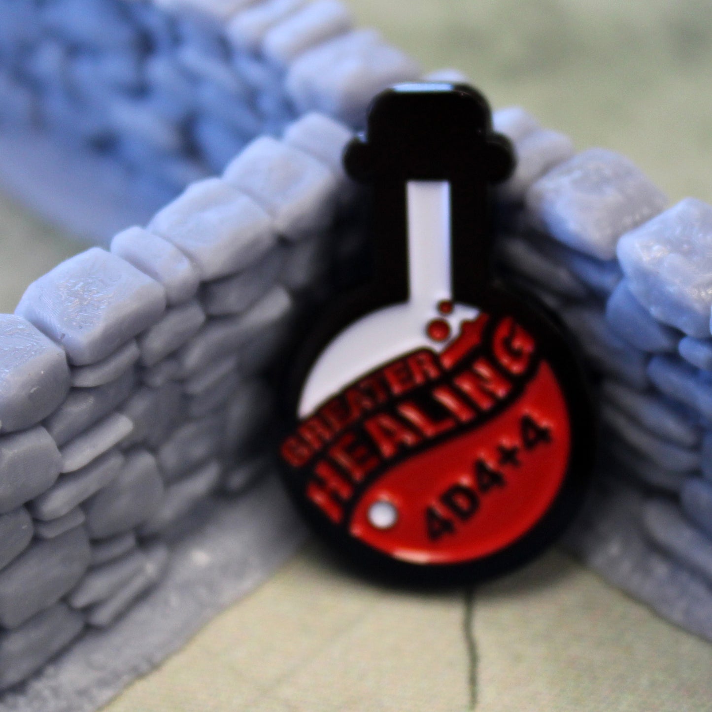 Greater Healing token is propped up in the corner where two pieces of gray stone wall set piece meet.