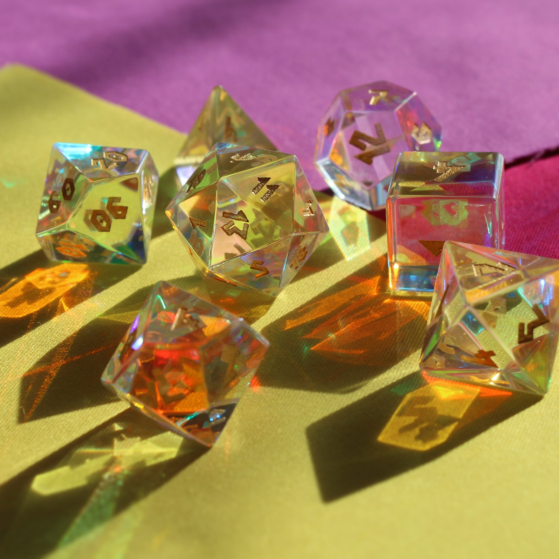 Dice Dungeons' Prismatic Glass dice set for tabletop RPGs arranged on a colorful surface casting shadows toward the viewer and refracting light in multiple directions.