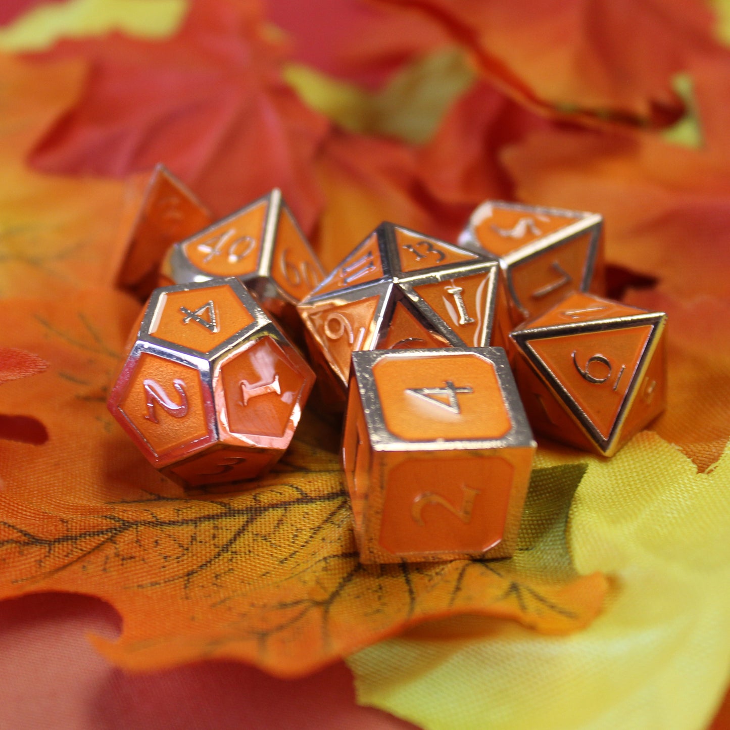 Imperial Pumpkin Spice dice scattered over a pile of fabric fall leaves.