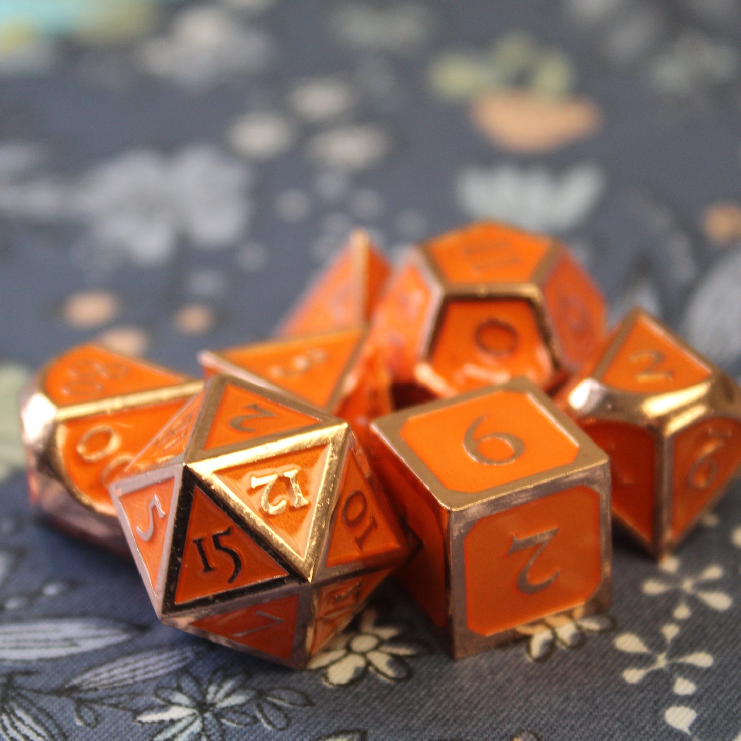 Imperial Pumpkin dice set scattered on top of a blue and white flower fabric.