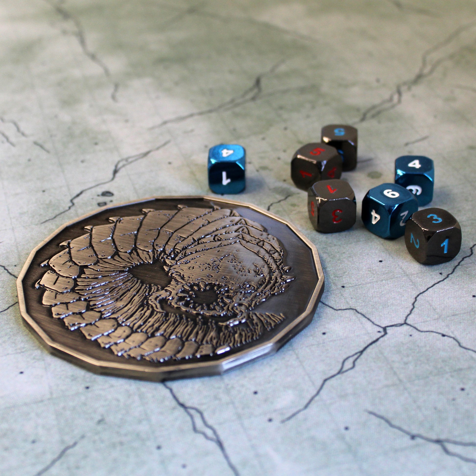 Purple Worm monster token next to polyhedral dice, showing its impressive 4-inch size for Dungeons & Dragons encounters.