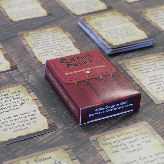 Partners in Crime Quest Deck laid on a table surrounded by small stacks of cards from the deck in a uniform grid across the table. The bottom of the quest deck box is in focus, which says "Dice Dungeons 2020 See More at DiceDungeons.com"