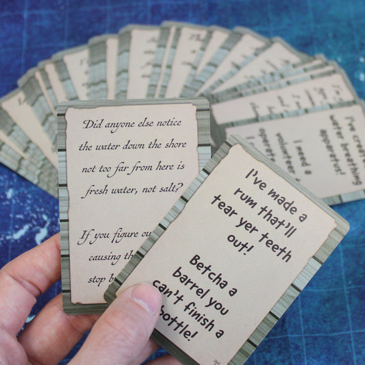 Two cards are fanned out in someone's hand, with the rest of the deck fanned out on a table below. One of the cards in the hand reads "I've made a rum that'll tear yer teeth out! Betcha a barrel you can't finish a bottle!" The cards fanned out below are on top of a blue game map.