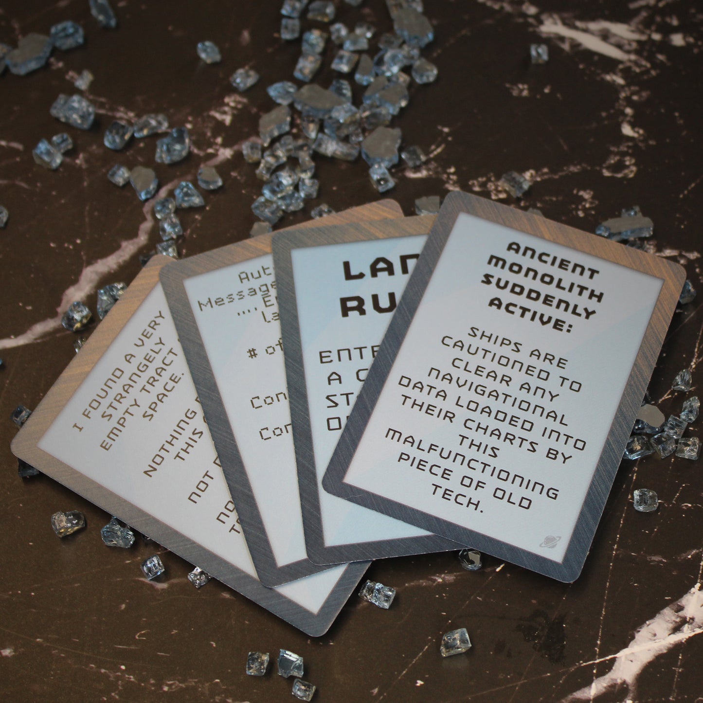 Example cards from Quest Decks: Into The Stars arranged in a fan. The top card reads "Ancient Monolith Suddenly Active: Ships are cautioned to clear any navigational data loaded into their charts by this malfunctioning piece of old tech." in all caps.