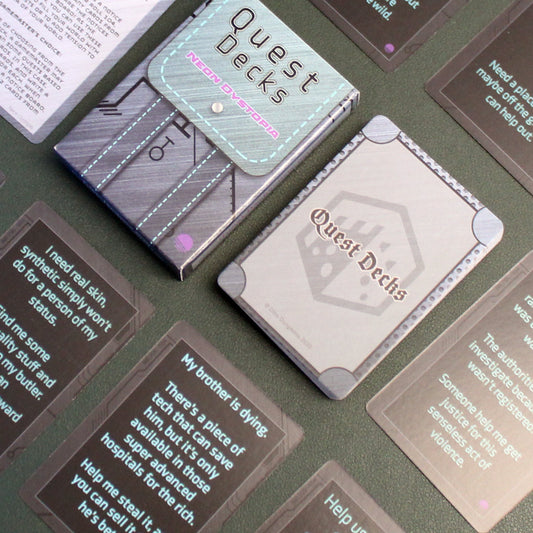 Neon Dystopia Quest Deck laid on a black table surrounded by small stacks of cards from the deck in a uniform grid across the table.