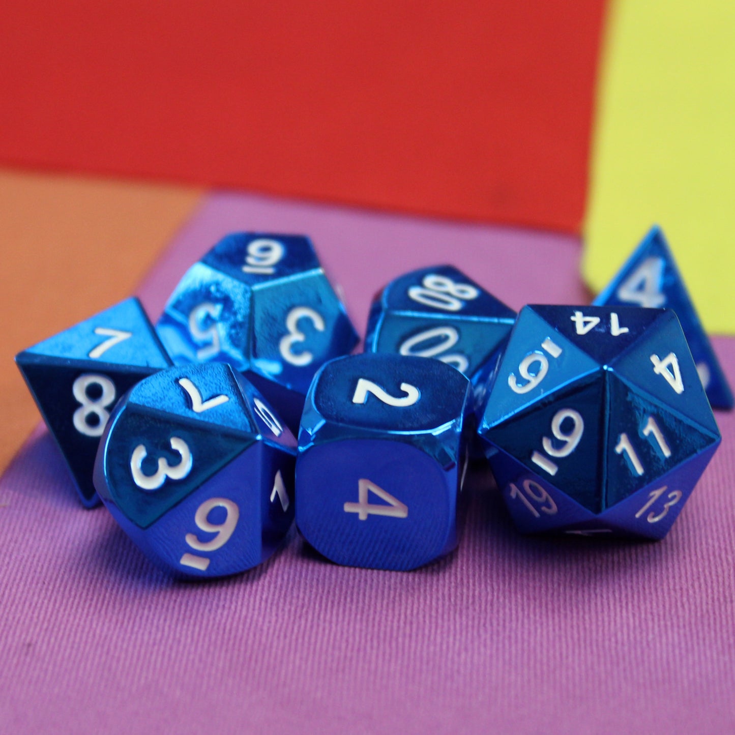 Radiant blue dice set scattered on a pink, orange, yellow, and red set piece.