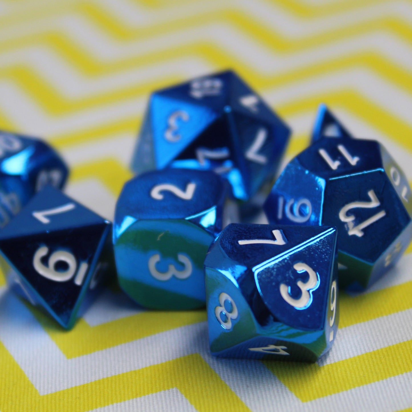 Radiant Blue dice set scattered on a yellow and white chevron patterned surface