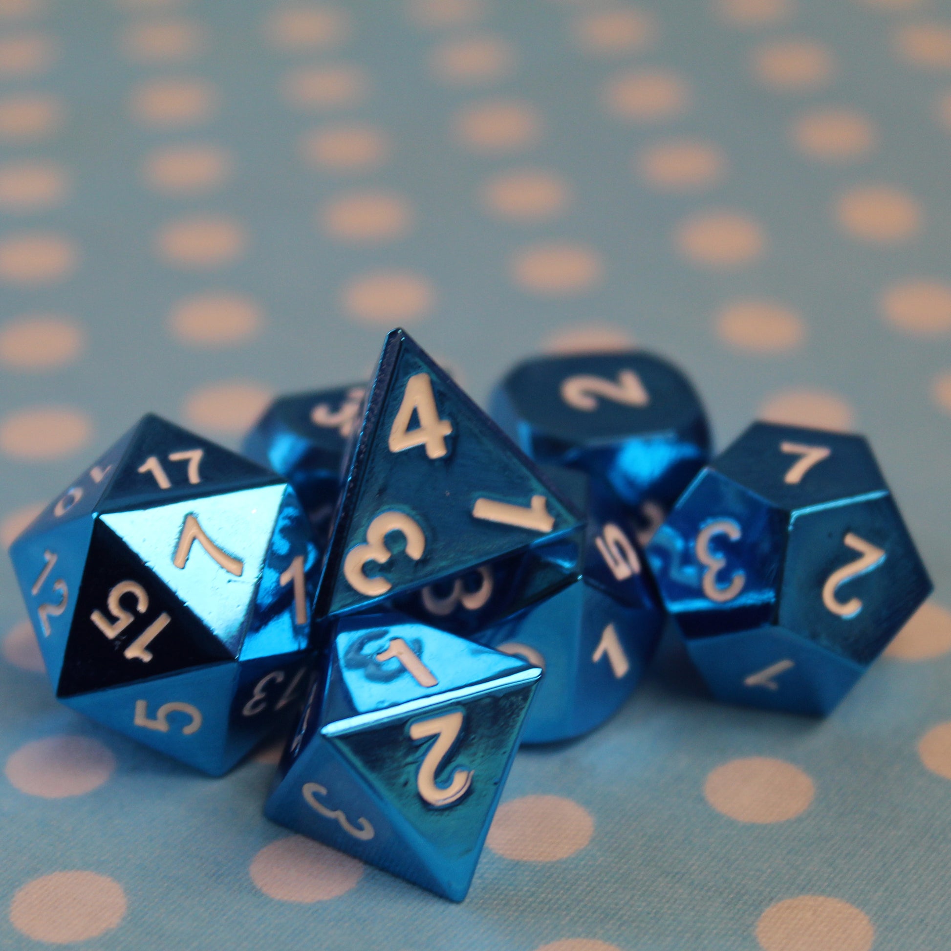 Radiant blue dice set scattered on a light blue fabric with white polka dots
