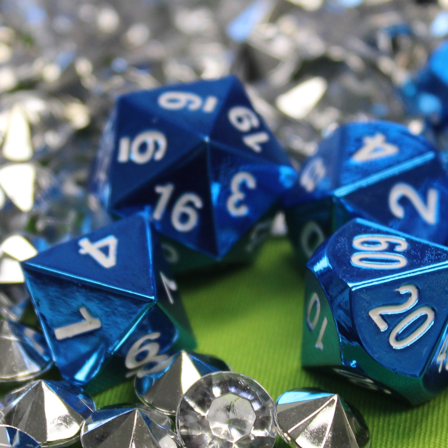 Close-up of some of the Radiant blue dice set scattered on a lime green surface with silvery gems surrounding them.