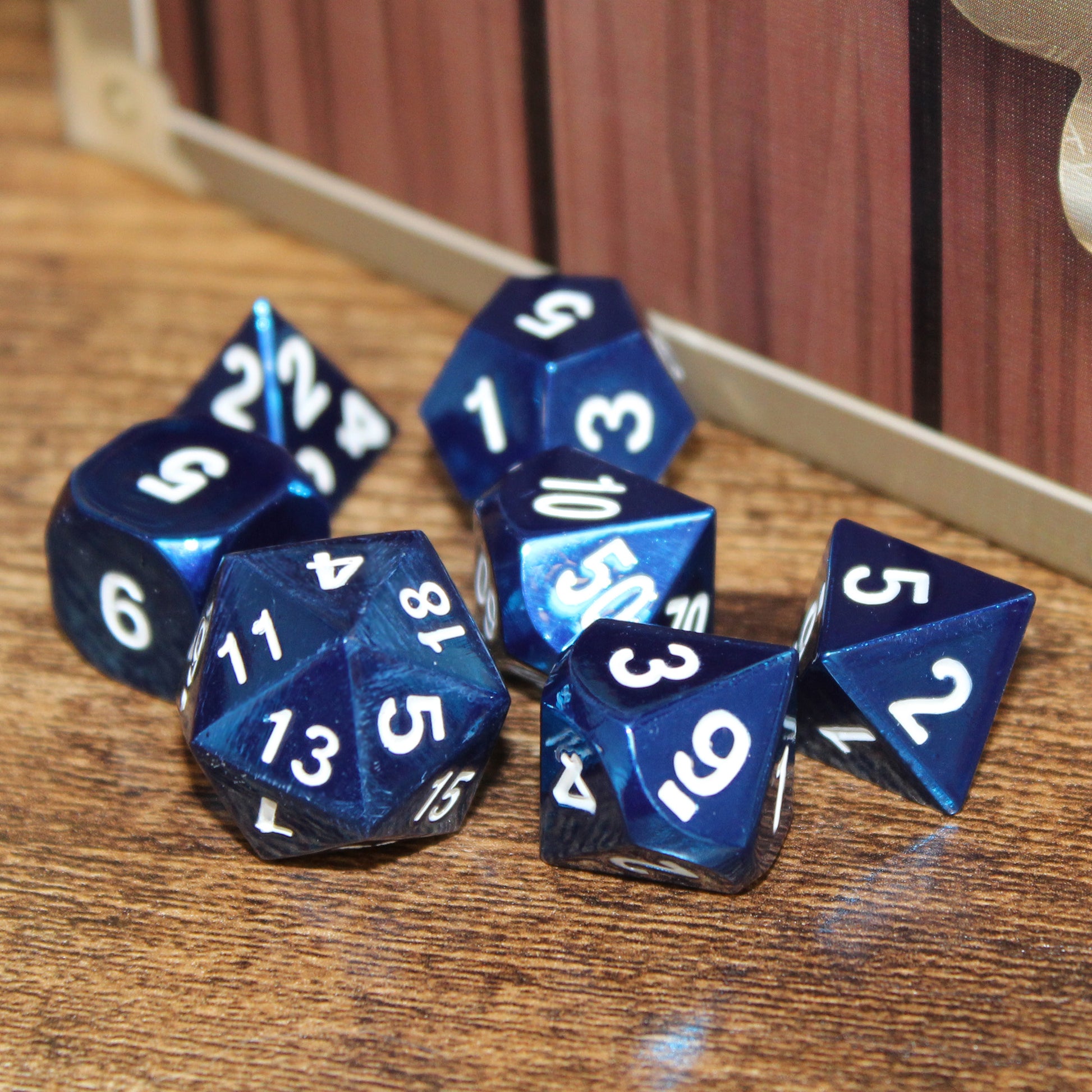 Radiant blue dice scattered on a wooden surface, with a Dice Dungeons card storage box behind them