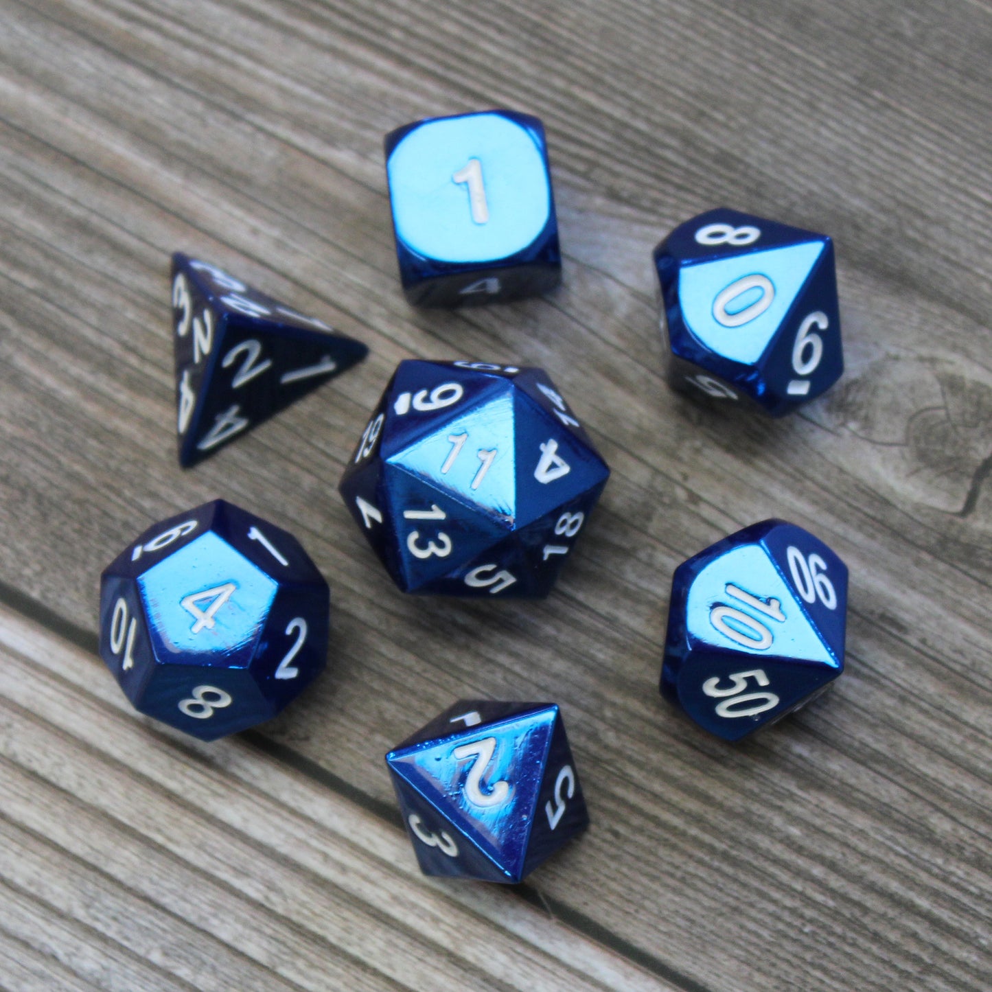 Radiant blue dice set arranged in a circle on a wooden surface, with the D20 in the center and the other dice surrounding it.