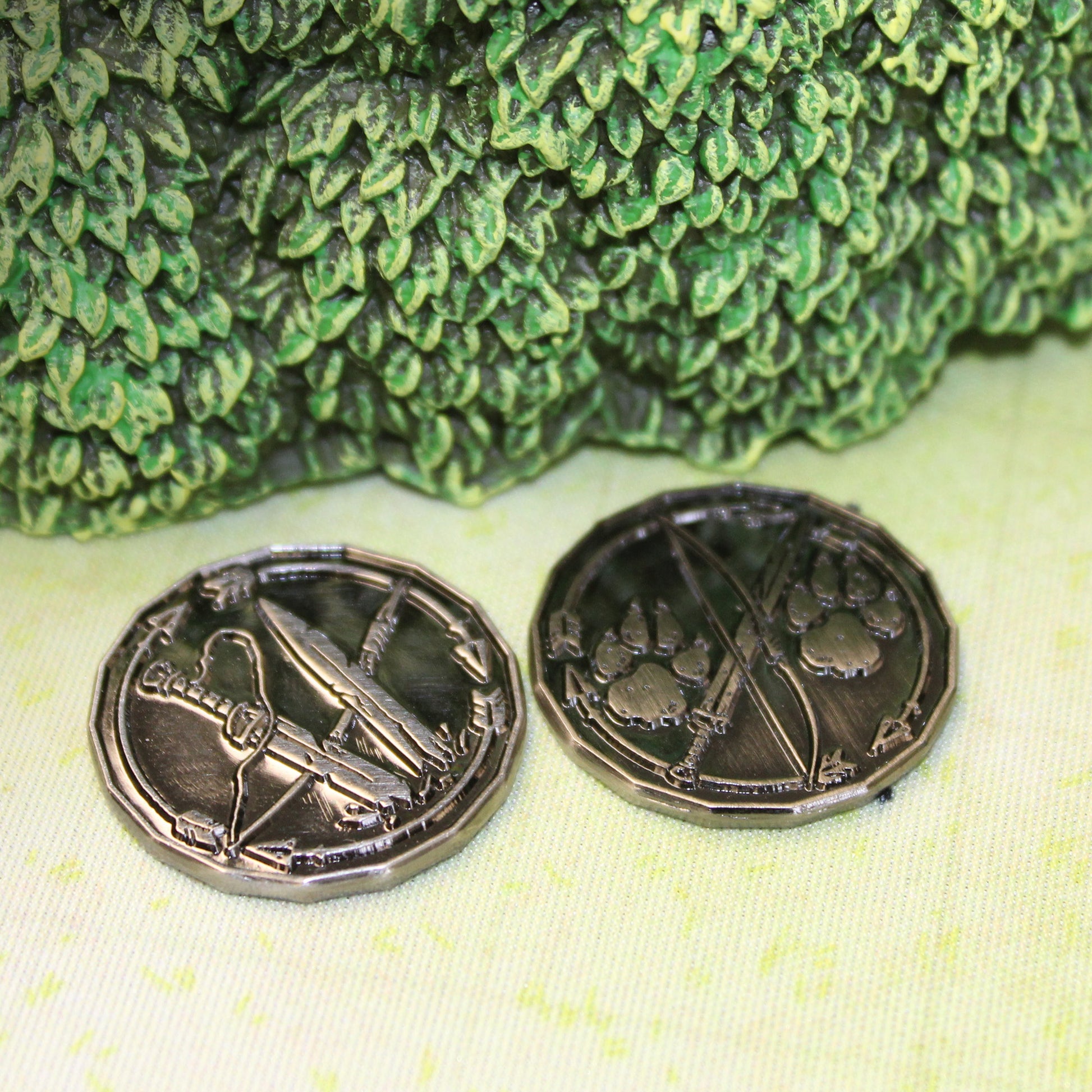 Two silver ranger character tokens on a light green play mat sitting next to a model bush