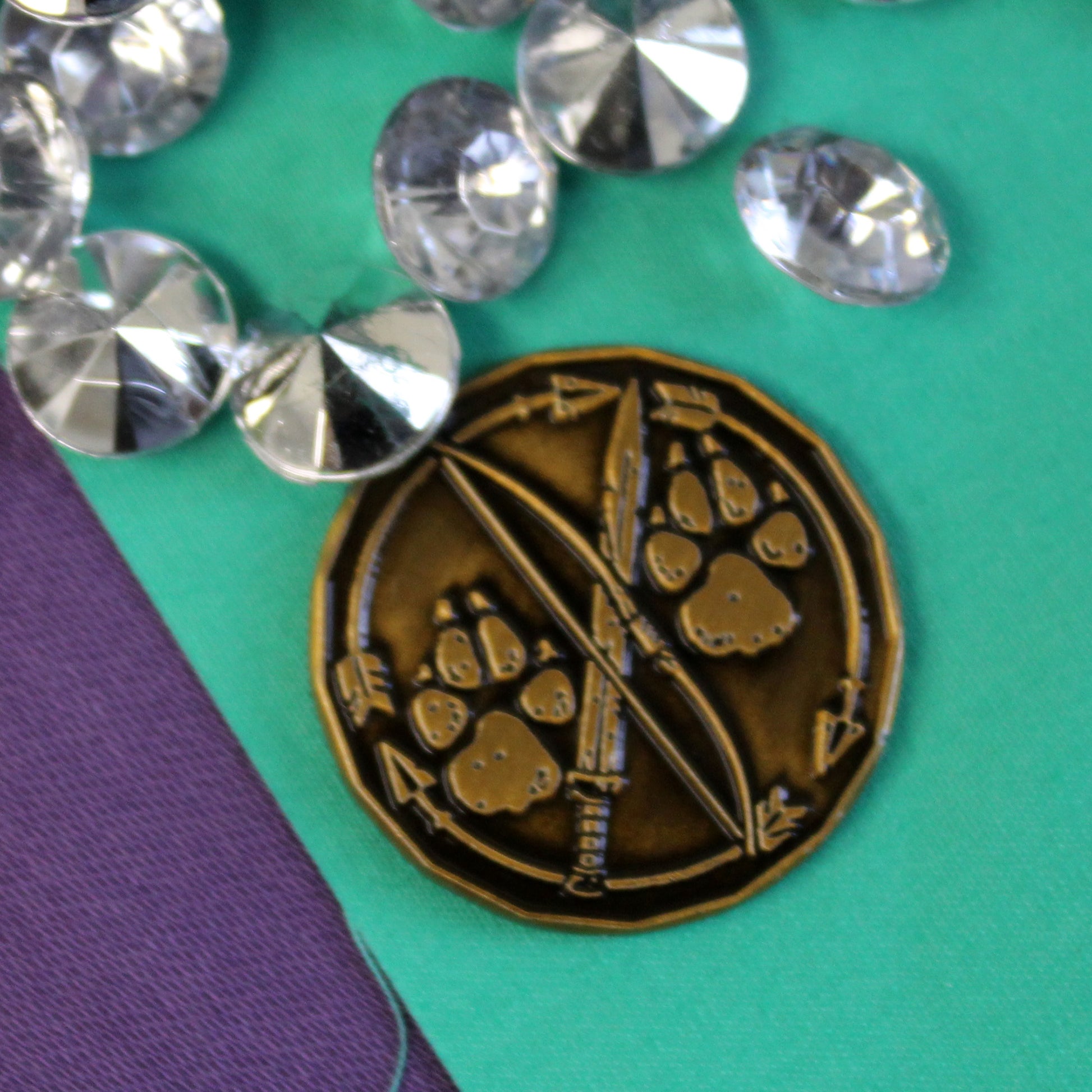 A golden ranger character token sitting on a green surface next to some scattered rhinestones.