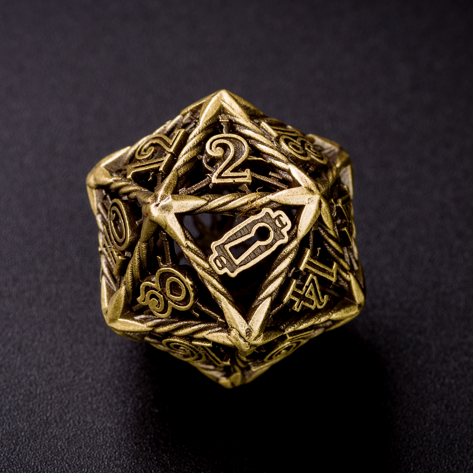 Up close bronze Rogue D20 die on a black surface. The die is turned to the 20 side, showcasing the replacement of the 20 with a keyhole.