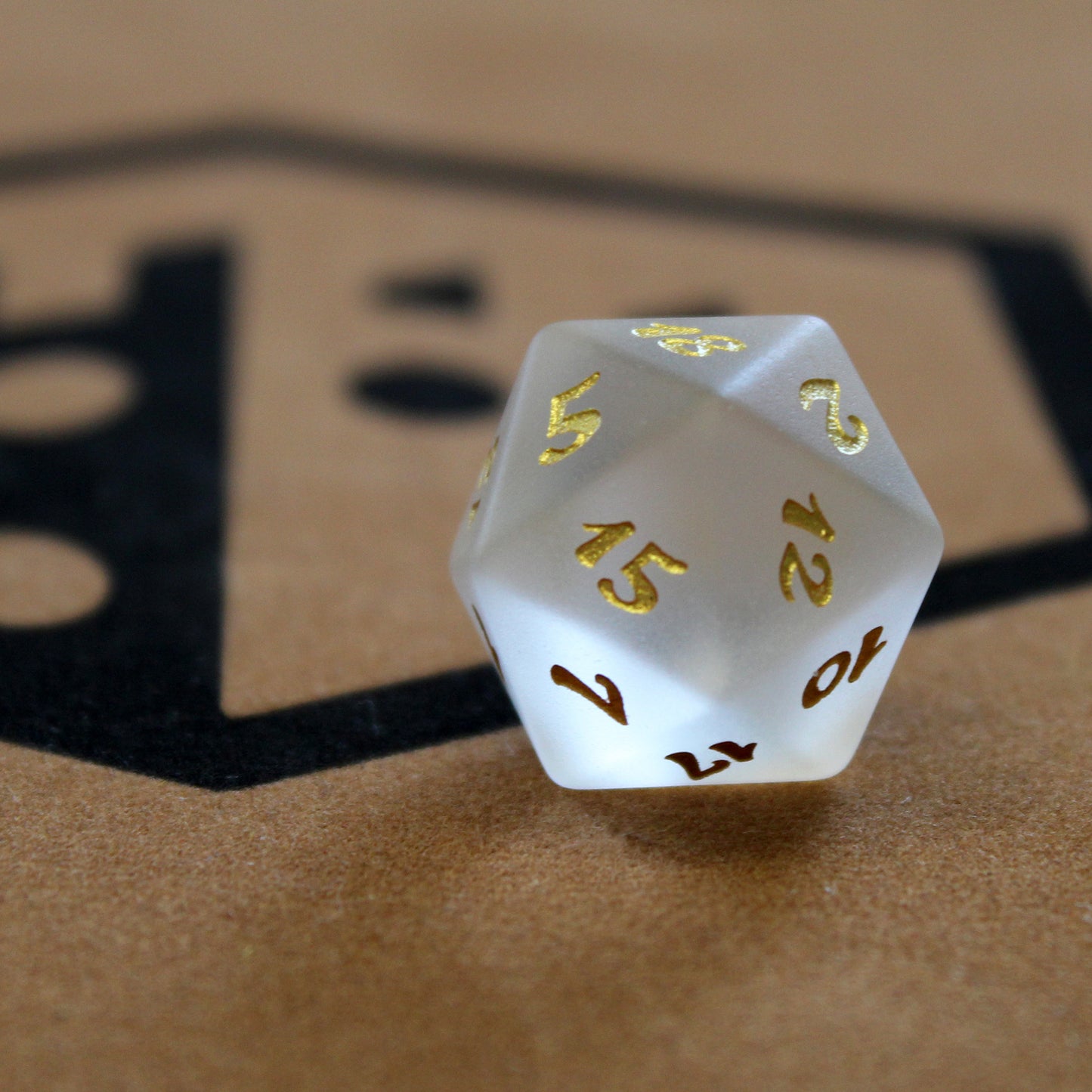 Set of white frosted glass RPG dice with golden font on a tray with the Dice Dungeons logo