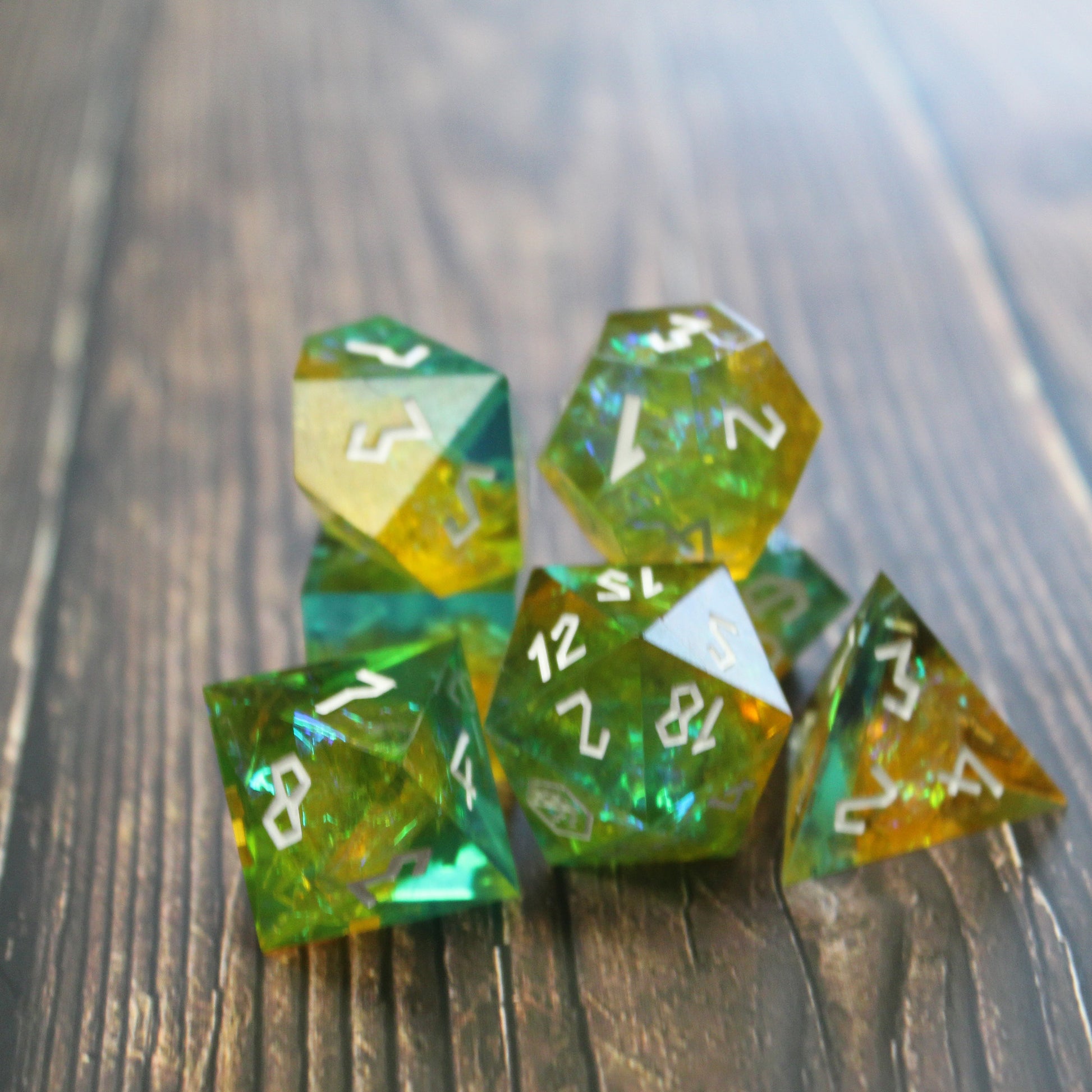 Full set of StarGlow Mutation Green Sharp Edge Resin Dice displayed on a wooden background, showcasing the green resin, iridescent inclusions, and silver Roman-inspired numbering.