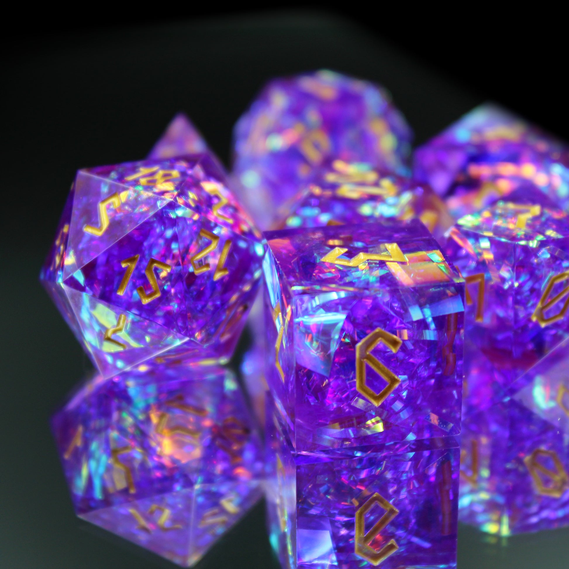 Closeup of StarGlow Purple dice set on a reflective. The closeup shows the gold numbers and iridescent material within the dice.
