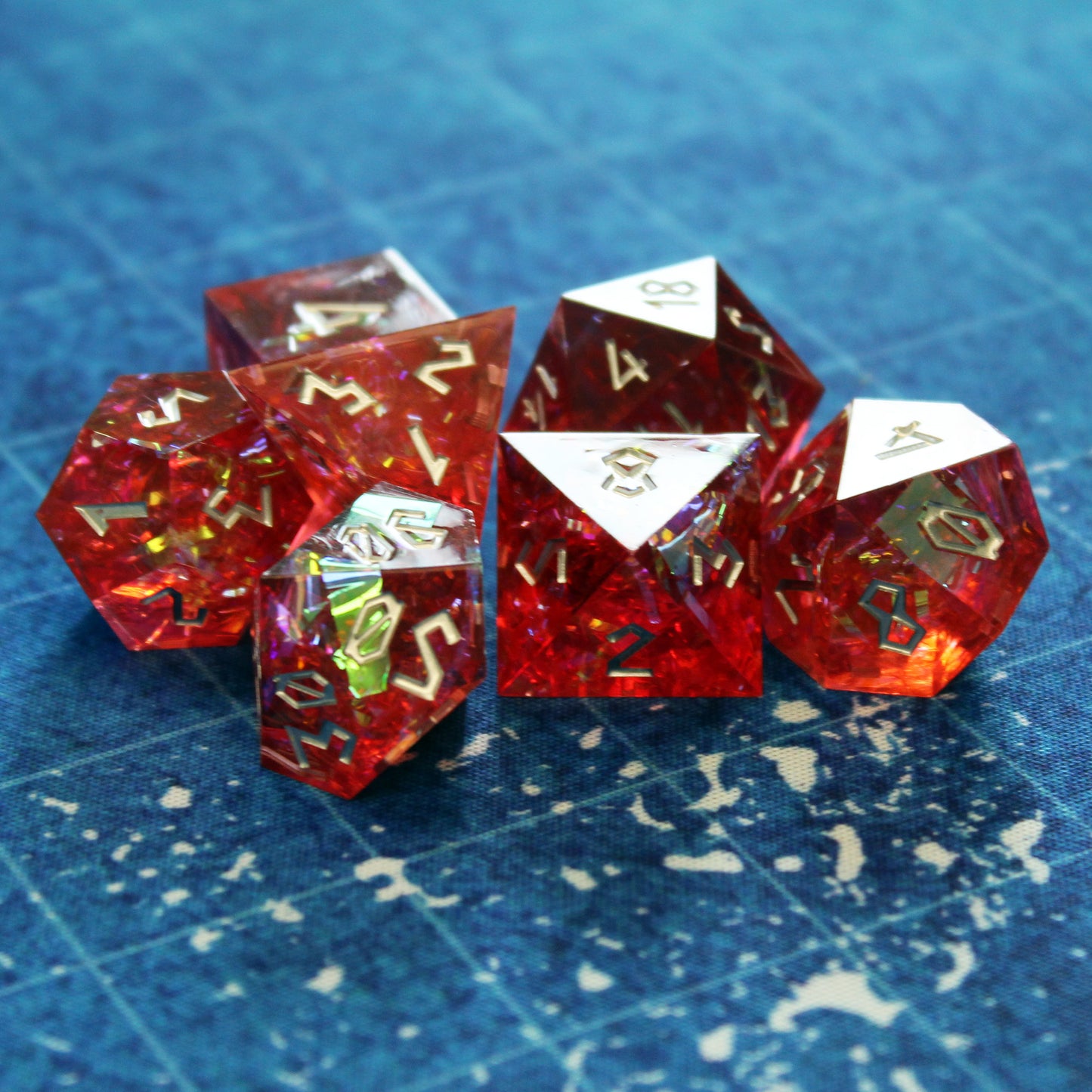 StarGlow Red resin dice set on an ocean battlemap, with translucent red resin and glowing iridescent inclusions.