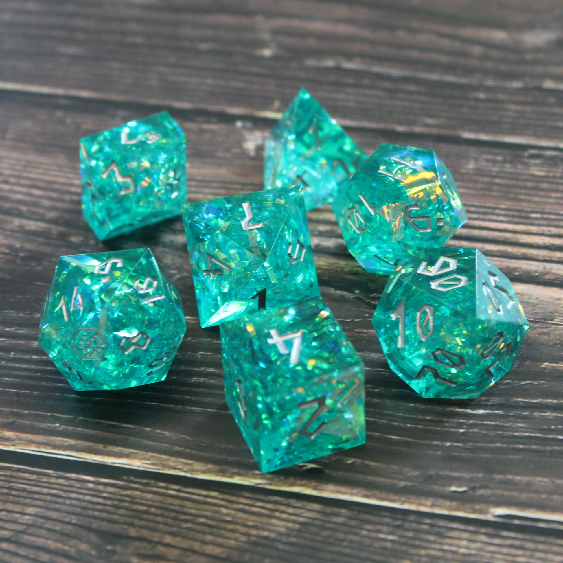 StarGlow Turquoise dice set on a table, featuring translucent blue-green resin and silver Roman-inspired numbering.