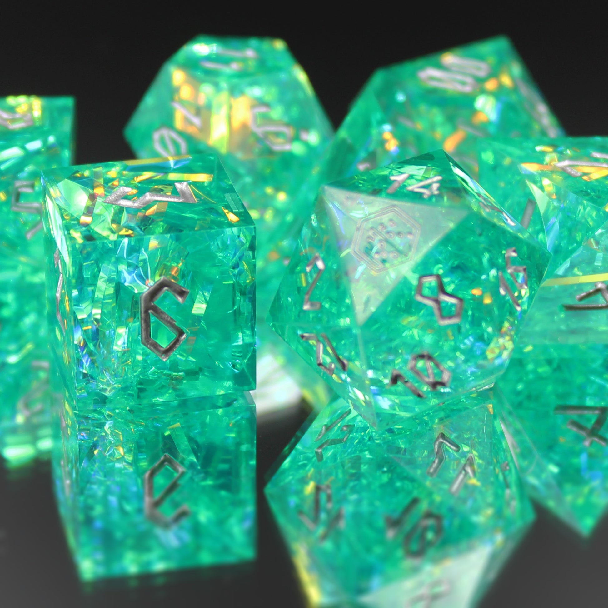 StarGlow Turquoise sharp edge resin dice set on a mirror, showing blue-green resin with iridescent inclusions.