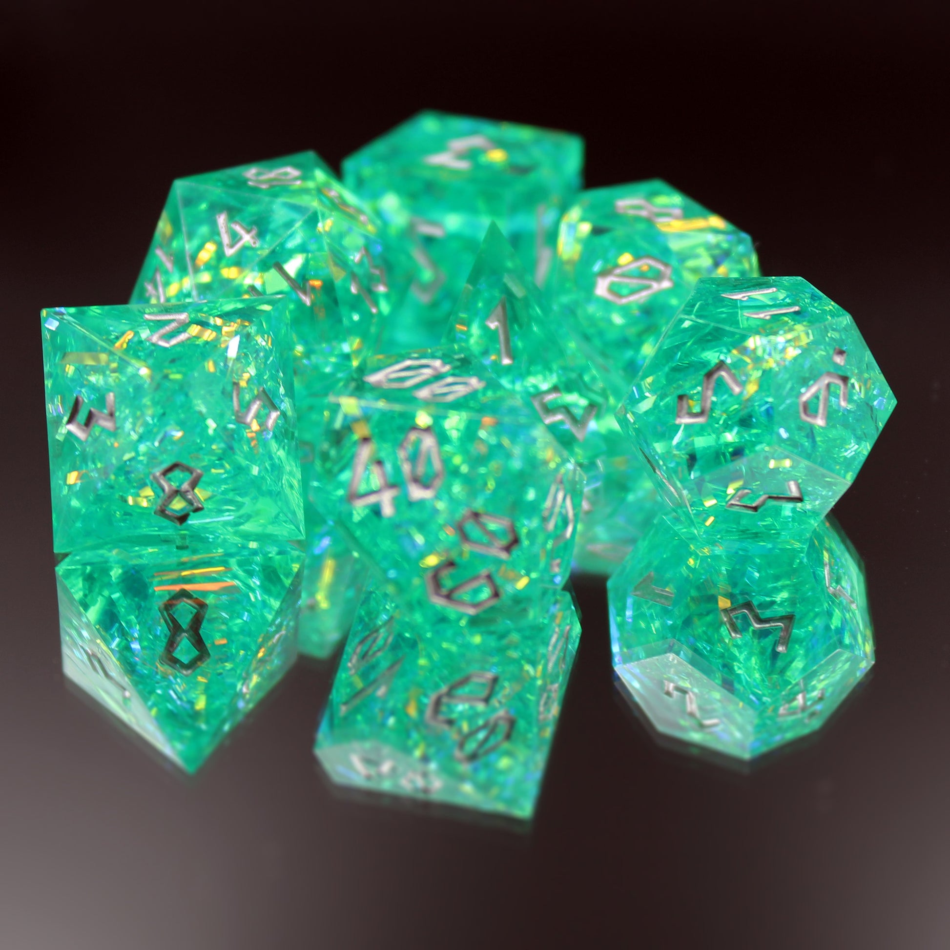 Green sharp edge resin dice set on a mirror, showing blue-green resin with iridescent inclusions.