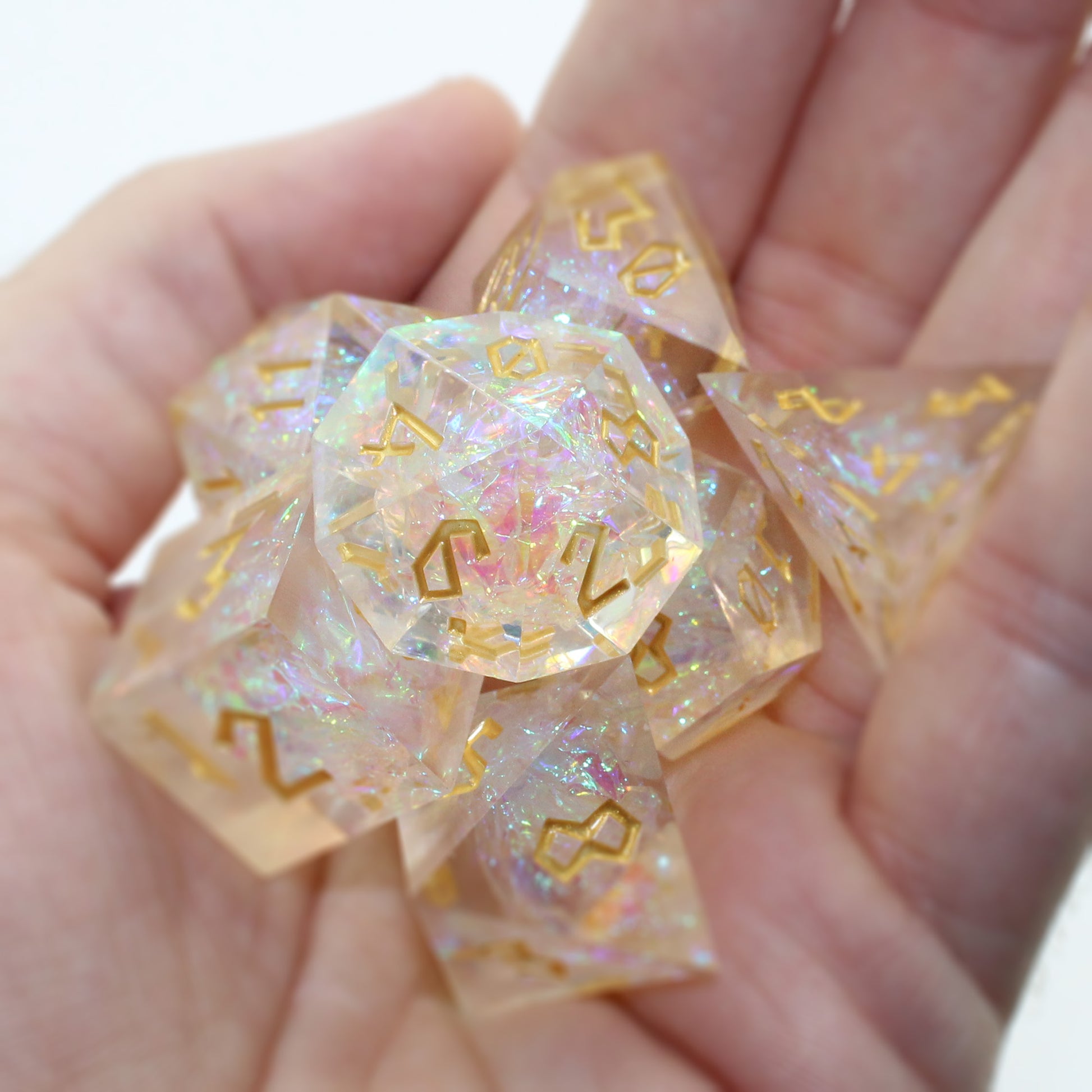 StarGlow White dice set arranged in a pile in the palm of someone's hand. The image emphasizes the gold numbers and iridescent glimmer within the dice.