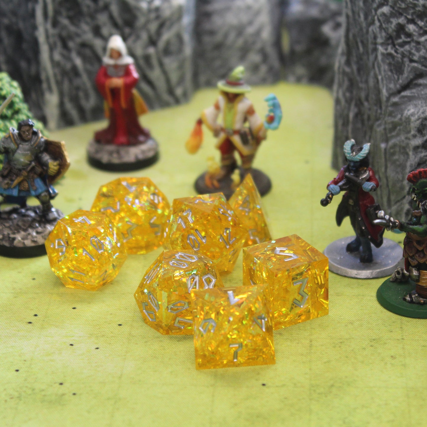 StarGlow Yellow sharp edge resin dice set surrounded by Dungeons & Dragons miniatures. Perfect for enhancing RPG gameplay.