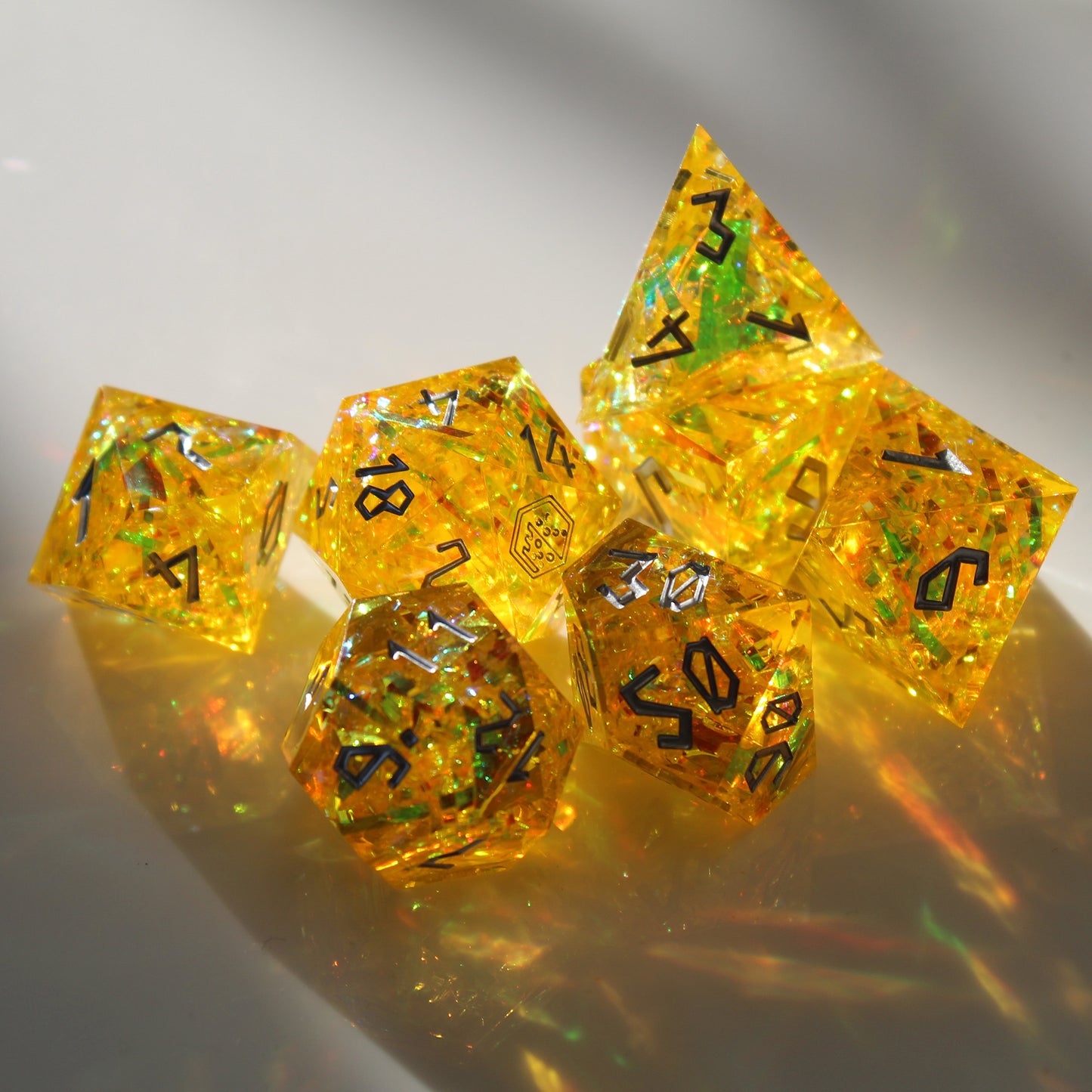 Full StarGlow Yellow dice set shown under light, revealing the glowing mylar foil and gold hues through the sharp-edged translucent resin.