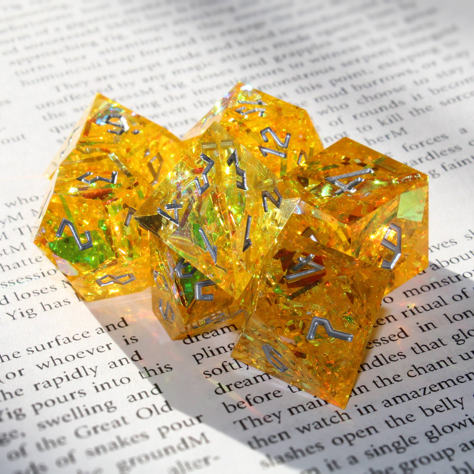 StarGlow Yellow sharp edge resin dice set displayed under bright light on an open book, with translucent yellow resin revealing shimmering green and gold hues, perfect for Dungeons & Dragons and other tabletop RPGs.