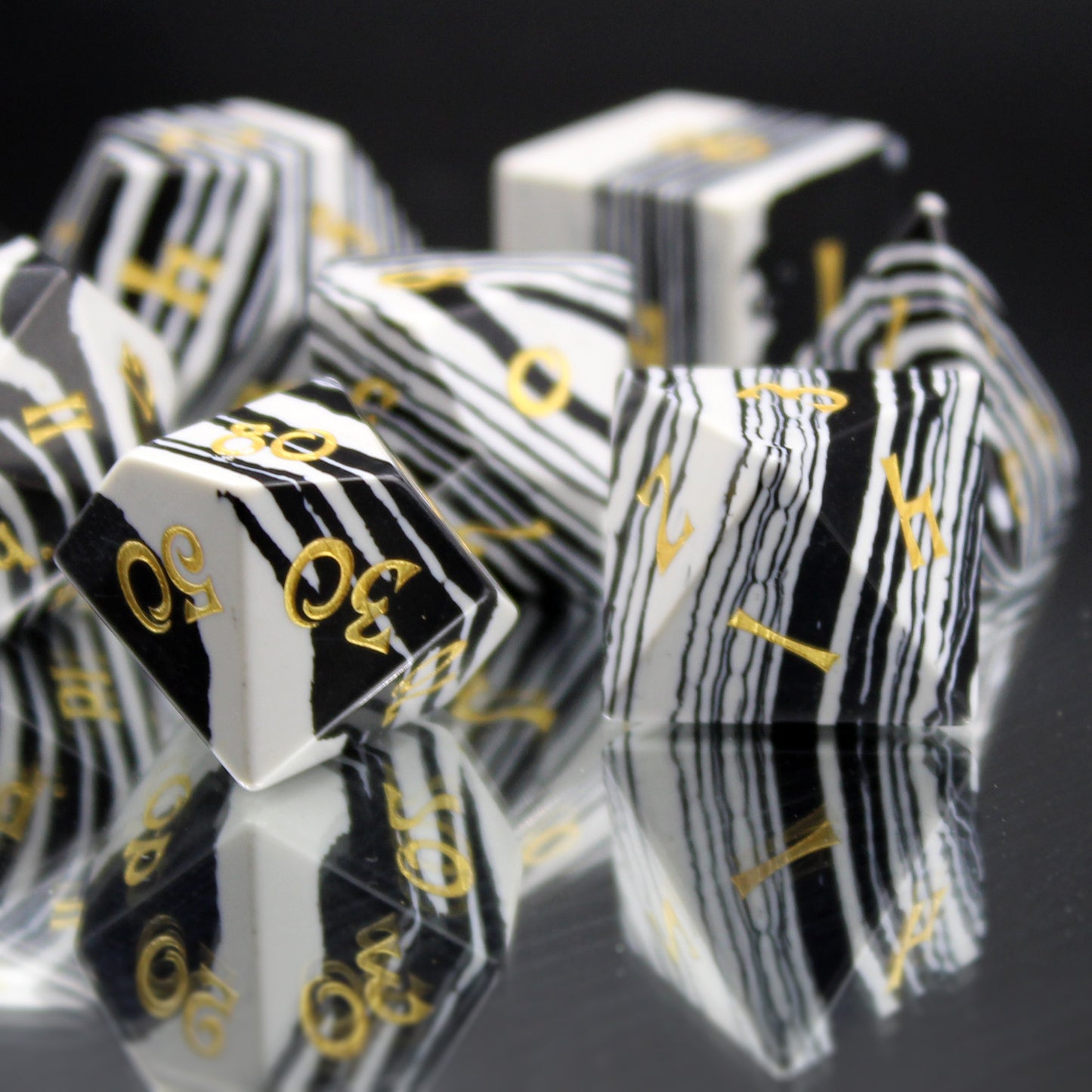 Close Up of Black and White Striped Dice with Gold Numbering on a Mirrored Background.