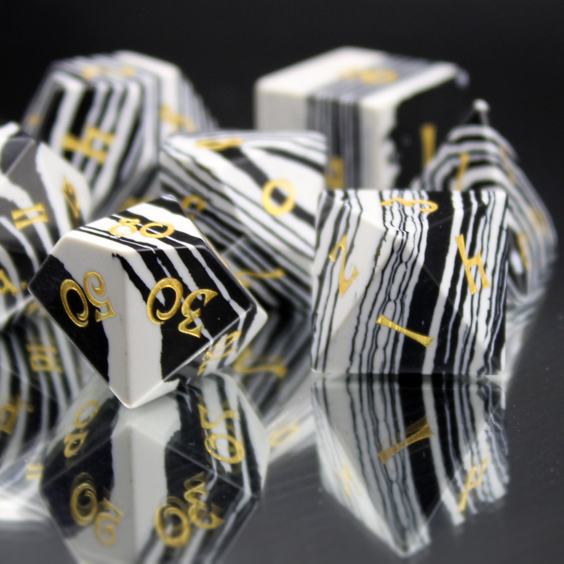 Close Up of Black and White Striped Dice with Gold Numbering on a Mirrored Background.