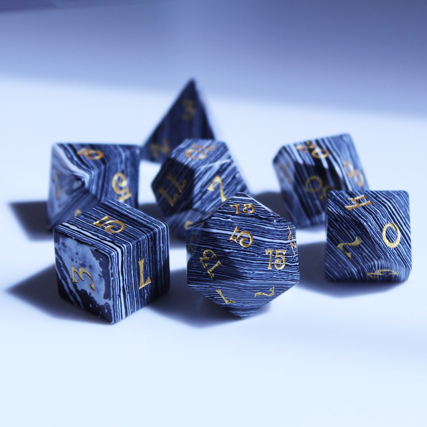 Set of Black and White Striped Dice with Gold Numbering Scattered on a White Background