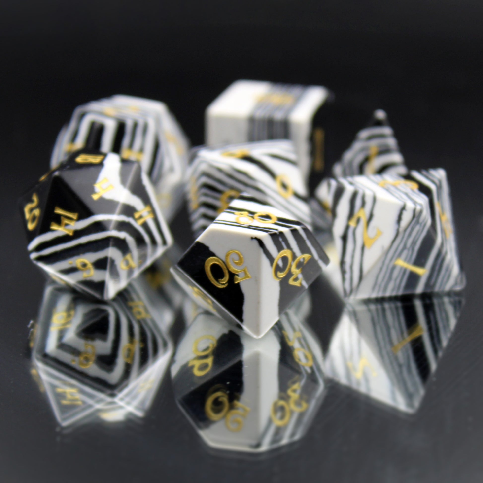Set of Black and White Striped Dice with Gold Numbering Scattered on a Mirrored Background