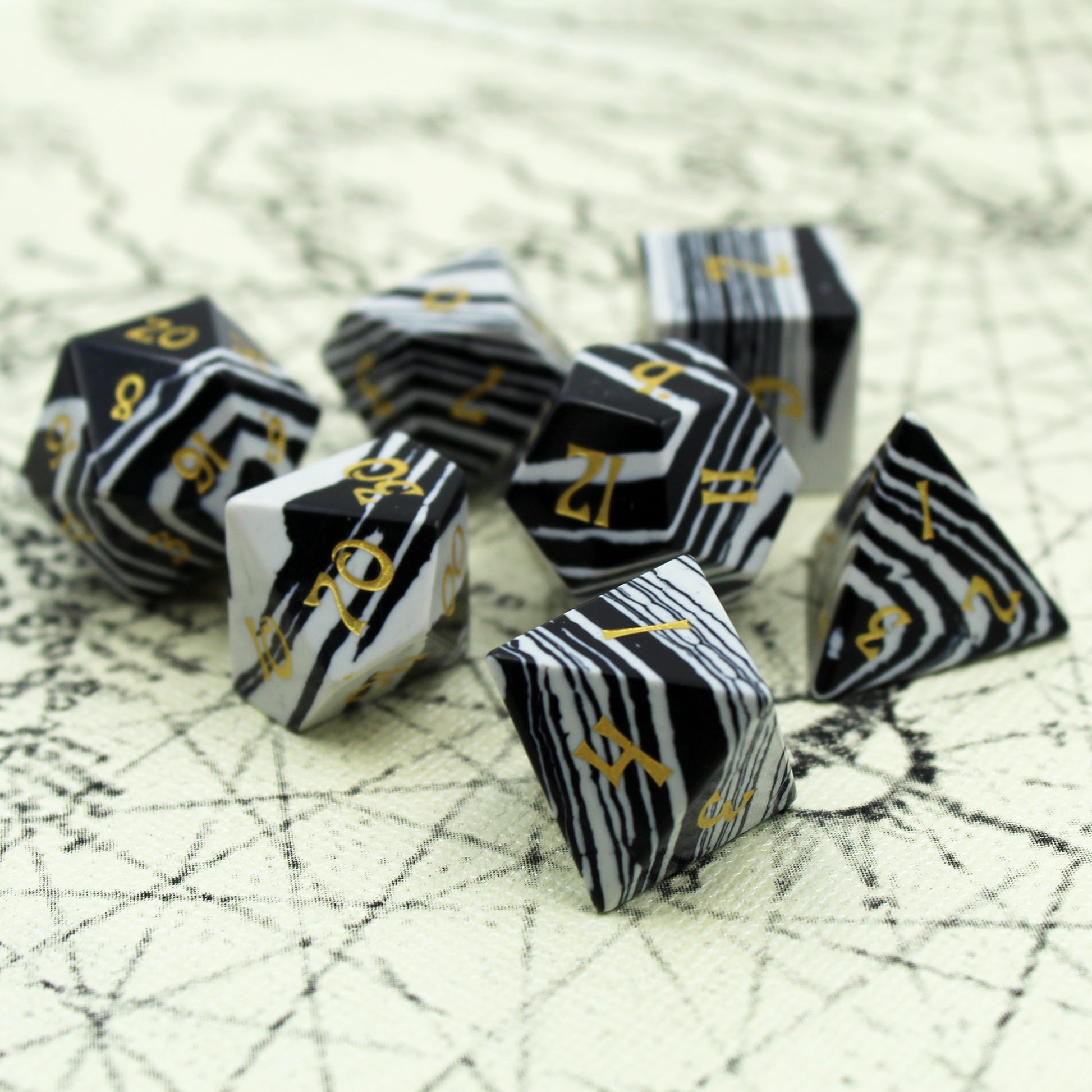 Set of Black and White Striped Dice with gold Numbering Scattered on a Parchment Background